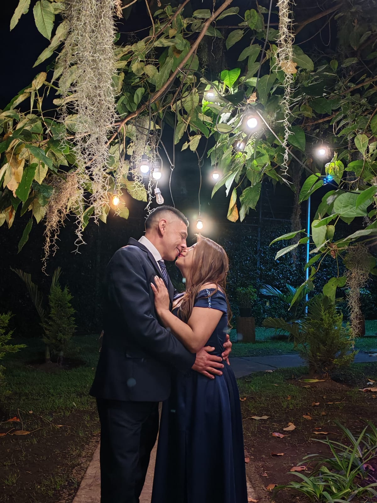 La pareja compartiendo un beso bajo las luces